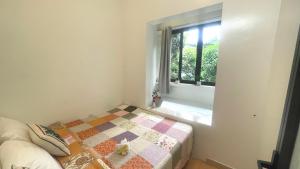 een slaapkamer met een quilt op een bed en een raam bij Lee Homestay in Hanoi