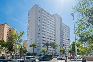 a tall white building with cars parked in a parking lot at Penthouse Cervantes Sea View Levante Beach in Benidorm