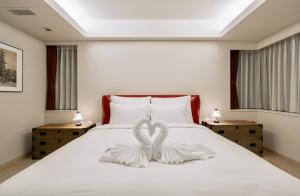a bedroom with a white bed with a heart shaped towel at Grand Phenix Hakuba by Jade Villa in Hakuba