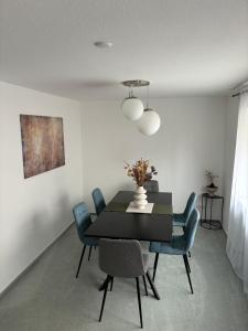 Deluxe Apartment Ella في باكنانغ: غرفة طعام مع طاولة سوداء وكراسي زرقاء