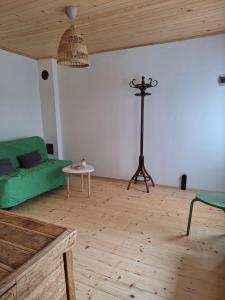 een woonkamer met een groene bank en een tafel bij Под шарената сянка in Kŭrpachevo