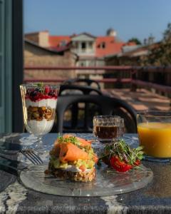 stół z talerzem jedzenia i dwie szklanki soku pomarańczowego w obiekcie Puris Moedani Boutique Hotel w mieście Tbilisi City