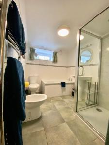 uma casa de banho com um WC e uma cabina de duche em vidro. em Lynwood House Bed and Breakfast em Tregoney