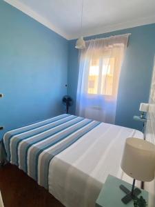 a blue bedroom with a bed and a window at MarePorto House in Fiumicino