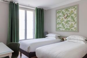 two beds in a room with green curtains and a window at Hôtel Saint Martin Bastille in Paris