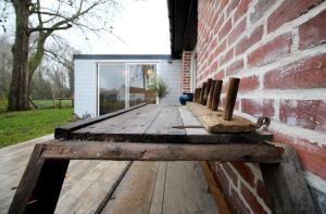 a wooden bench sitting next to a brick wall at La Forge d'Espérance in Éperlecques