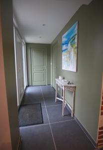 a hallway with a table and a painting on the wall at La Forge d'Espérance in Éperlecques +3 photos