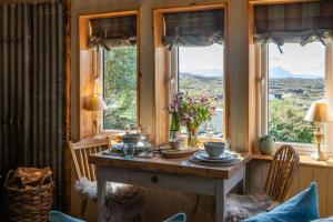 a dining room with a table in a room with windows at Luxury self catering 1 bed cottage with log burner in Applecross +5 photos