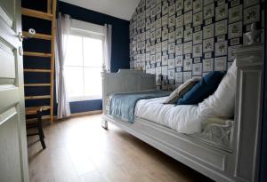 a bedroom with a white bed with a wall of pictures at La Forge d'Espérance in Éperlecques