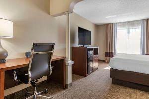 um quarto de hotel com uma cama e uma secretária com um computador em Comfort Suites Grandville em Grandville