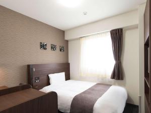 a hotel room with a bed and a window at Comfort Hotel Wakayama in Wakayama