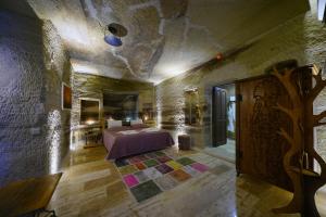 Göreme Cave Lodge في غوريمِ: غرفة نوم بسرير في جدار حجري