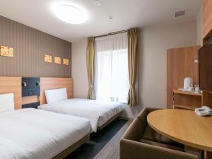 a hotel room with two beds and a table at Comfort Hotel Osaka Shinsaibashi in Osaka
