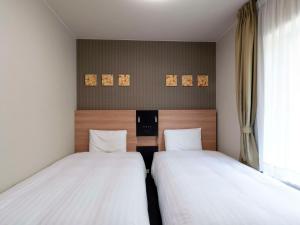 two twin beds in a room with a window at Comfort Hotel Osaka Shinsaibashi in Osaka