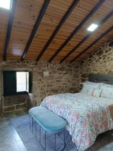 a bedroom with a bed and a stone wall at A Casiña de Arretén in Padrón