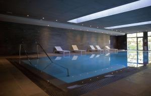 una gran piscina con sillas en un edificio en Clarion Paris CDG Airport en Roissy-en-France