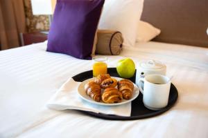 a tray with a plate of pastries on a bed at Clarion Paris CDG Airport in Roissy-en-France