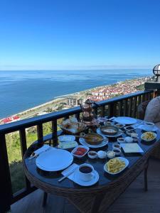 una mesa con comida en la parte superior de un balcón con la playa en Günbatımı Bungalov, en Rize