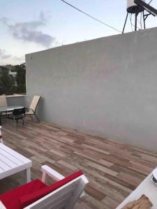 eine Terrasse mit Tischen und Stühlen und einer weißen Wand in der Unterkunft Big quiet Cottage in centre Raanana in Ra‘ananna