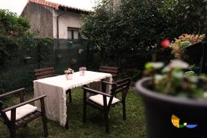 a table with chairs and a white table cloth on a yard at Adosado en LLanes in Llanes