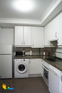a kitchen with white cabinets and a washer and dryer at Adosado en LLanes in Llanes
