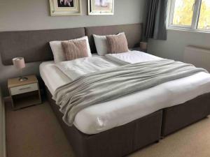 ein großes Bett in einem Schlafzimmer mit einem Nachttisch in der Unterkunft Warwick House, 5 bedrooms, 9 beds, parking, garden in Coventry