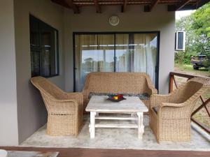 a patio with wicker chairs and a table on a porch at Nkumbe 7C in Ponta Malangane