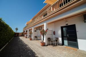 - un bâtiment avec une porte noire, des chaises et des plantes dans l'établissement Aparthotel Solifemar, à Castelldefels