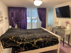 a bedroom with a bed with purple curtains and a television at Luxus Domizil in Villingen-Schwenningen
