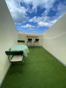 a room with a table and chairs in a room with green carpet at Seaside room in a Peniche townhouse featuring a private bathroom and shared access to the swimming pool and kitchen in Atouguia da Baleia