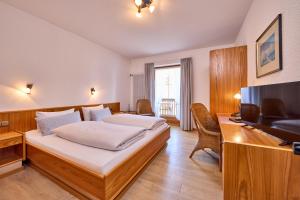 a bedroom with a bed and a desk and a television at Hotel Antonia in Oberammergau