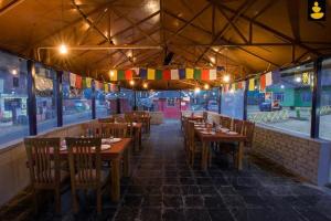 比尔瓦Siddhartha Greens Resort Bir Billing Amidst Tea Garden的餐厅设有木桌、椅子和旗帜