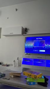 a living room with a tv and a table with books at Al Ashkhara Beach House in Al Sharqiyah