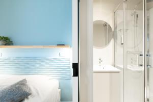 een slaapkamer met een glazen douche en een wastafel bij Hotel José in Blankenberge