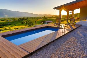 a swimming pool with a wooden deck next to a house at Villa Bubinka in Bihać