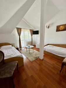 duża sypialnia z 2 łóżkami i stołem w obiekcie PENSIUNEA ANA w mieście Piatra Neamţ