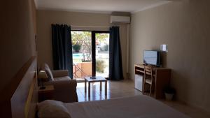 a bedroom with a bed and a television and a chair at Vilamar in Luz