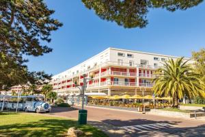 un grand bâtiment avec une voiture garée devant dans l'établissement Le Grain de Sable, à Royan
