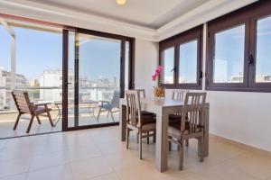 una sala da pranzo con tavolo, sedie e finestre di Cityscape Loft a Città di Rodi