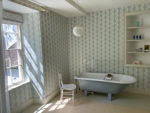 łazienka z wanną, krzesłem i oknem w obiekcie Noyadd Trefawr w mieście Cardigan