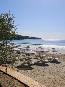 a beach with umbrellas and chairs and the ocean at Olive Villas Beach Hotel in Sozopol