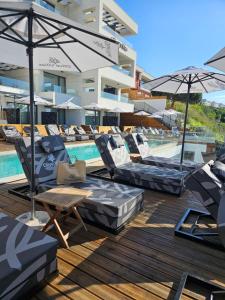 a group of lounge chairs and umbrellas next to a swimming pool at Olive Villas Beach Hotel in Sozopol