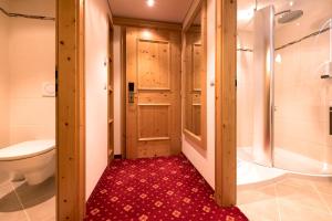 łazienka z prysznicem, toaletą i czerwonym dywanem w obiekcie Hotel Bergkristall w mieście Silbertal
