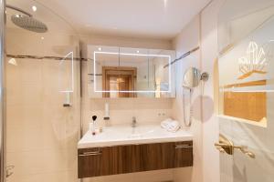 W łazience znajduje się umywalka, lustro i prysznic. w obiekcie Hotel Bergkristall w mieście Silbertal