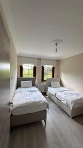 two beds in a large room with two windows at Kaya Palace in Uzungöl