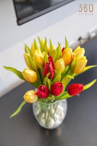 eine Vase mit gelben und roten Blumen auf einem Tisch in der Unterkunft Plan Court Seaside Suites in Qawra by 360 Estates in St Paul's Bay