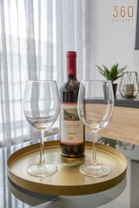 eine Flasche Wein und zwei Weingläser auf einem Tablett in der Unterkunft Plan Court Seaside Suites in Qawra by 360 Estates in St Paul's Bay