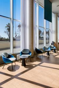 a waiting room with chairs and tables and windows at B&B HOTEL Barcelona Viladecans in Viladecáns