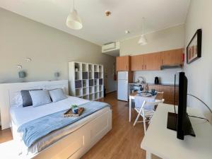a bedroom with a large bed and a kitchen at Oporto Trindade Residence in Porto