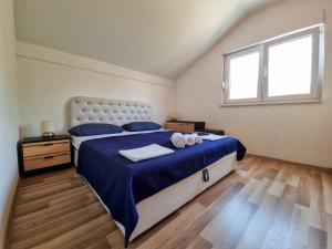 a bedroom with a large bed with blue sheets and a window at Holiday Home Vemini in Mostar